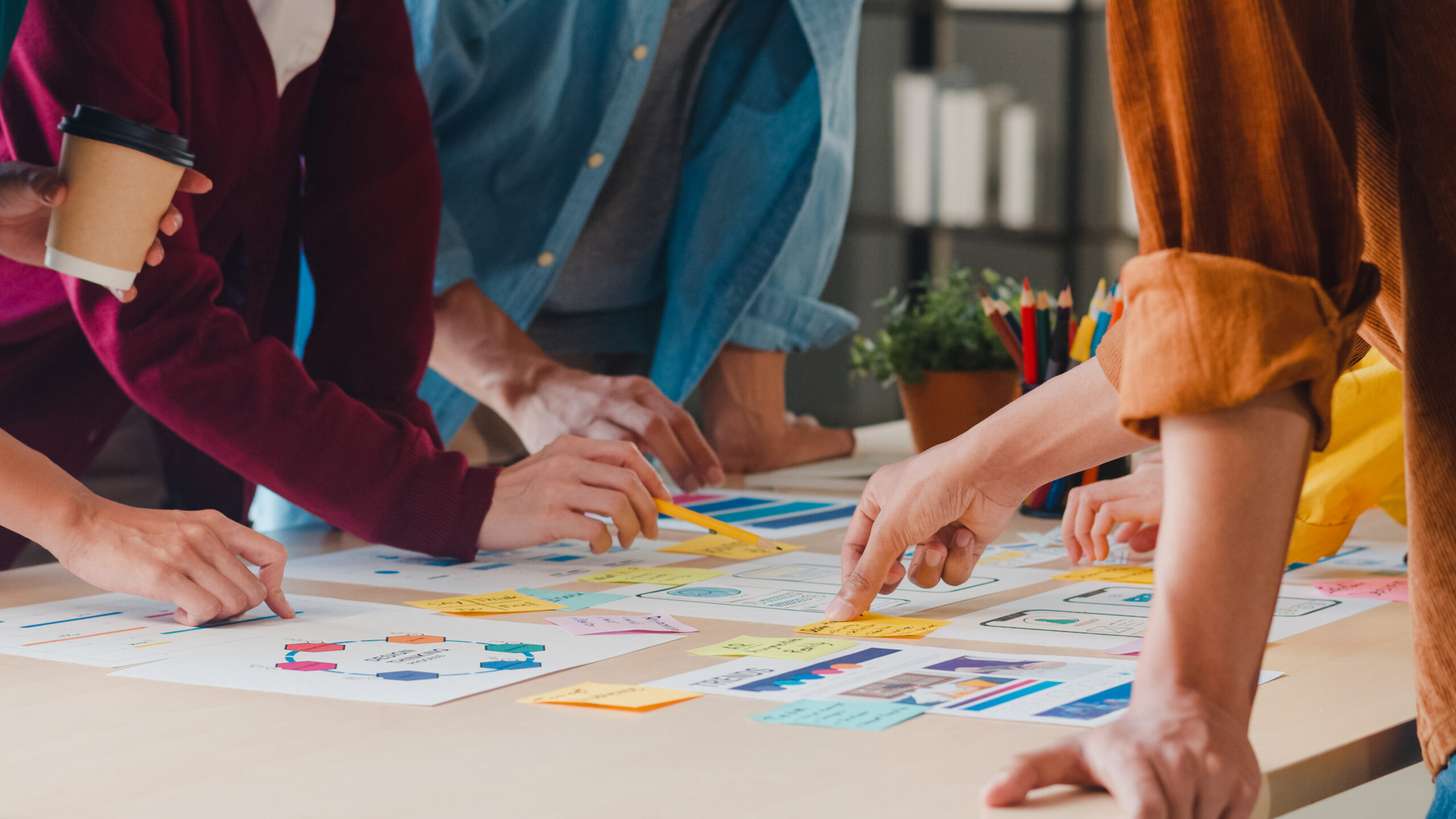 businessmen and businesswomen meeting brainstorming ideas about creative web design planning application and developing template layout for mobile phone project working together in small office.